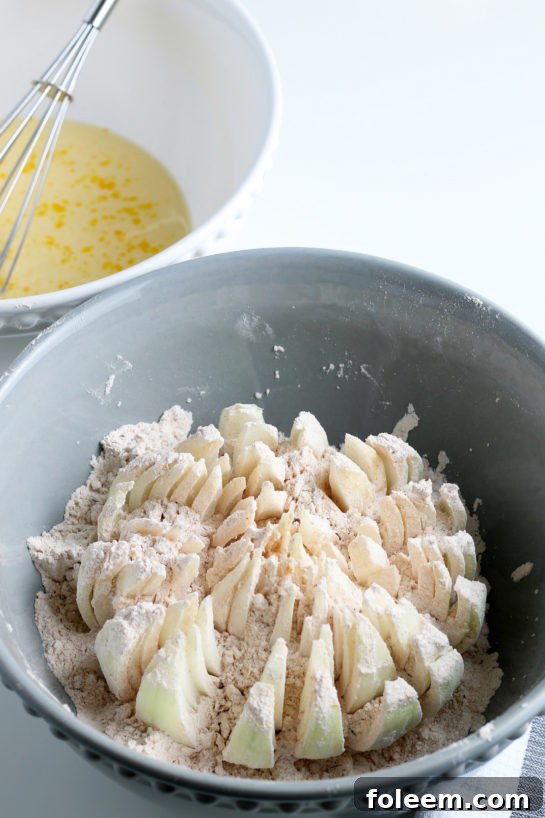 A sliced blooming onion being thoroughly dipped into a seasoned batter, ensuring every petal is coated evenly.