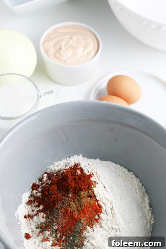 Various dry ingredients such as flour, paprika, and other spices being added to a mixing bowl for the blooming onion batter.