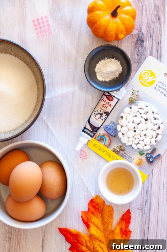 A collection of ingredients laid out, including eggs, sugar, cream of tartar, and vanilla, for making Halloween Boo Meringues.