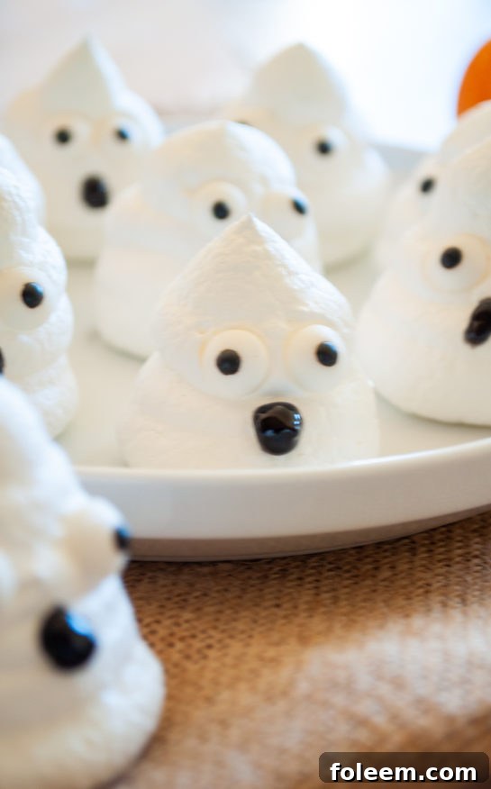 A close-up shot of multiple cute and simple Halloween Boo Meringues, each with unique eyes, arranged on a festive plate.