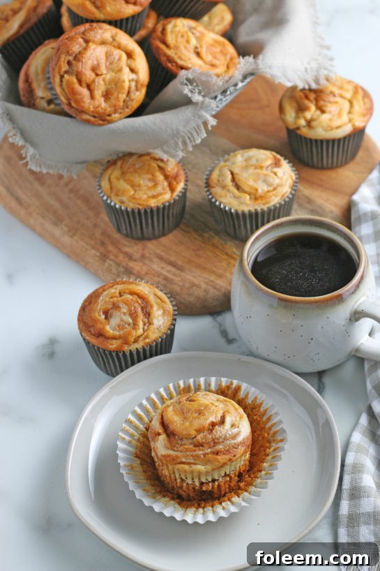Beautifully baked Pumpkin Cream Cheese Swirl Muffins arranged elegantly, ready for a cozy breakfast or a festive fall, Halloween, or Thanksgiving gathering.