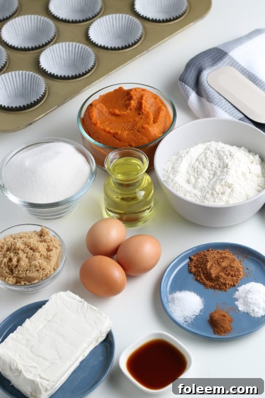 Collection of fresh ingredients for baking Pumpkin Cream Cheese Swirl Muffins, including pumpkin puree, flour, sugar, and spices.