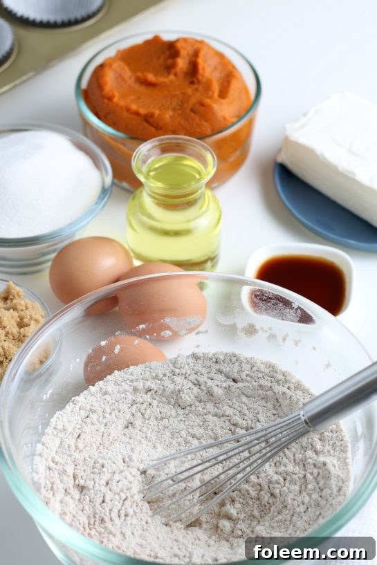A whisk smoothly combining the dry ingredients in a bowl, preparing for the wet ingredients of the pumpkin muffin batter.