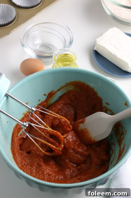 The process of gently mixing pumpkin puree with the pre-combined dry ingredients to form the base of the pumpkin muffins.