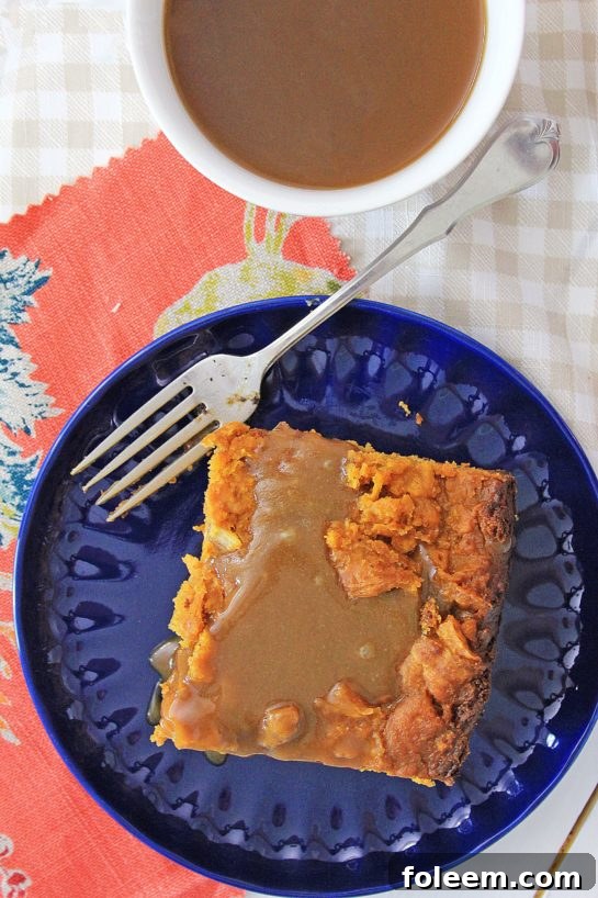 Serving individual portions of slow cooker pumpkin bread pudding topped with rich caramel sauce.