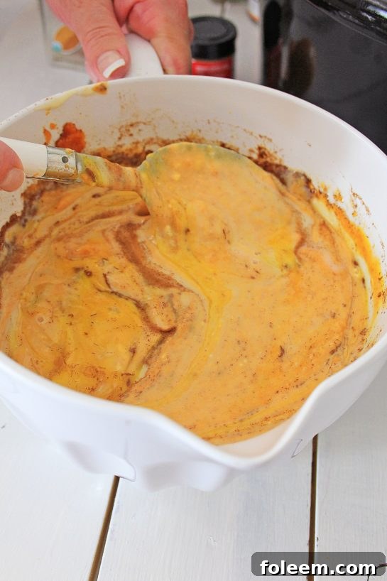 Mixing wet ingredients thoroughly to create the luscious custard base for Crock Pot Pumpkin Bread Pudding.