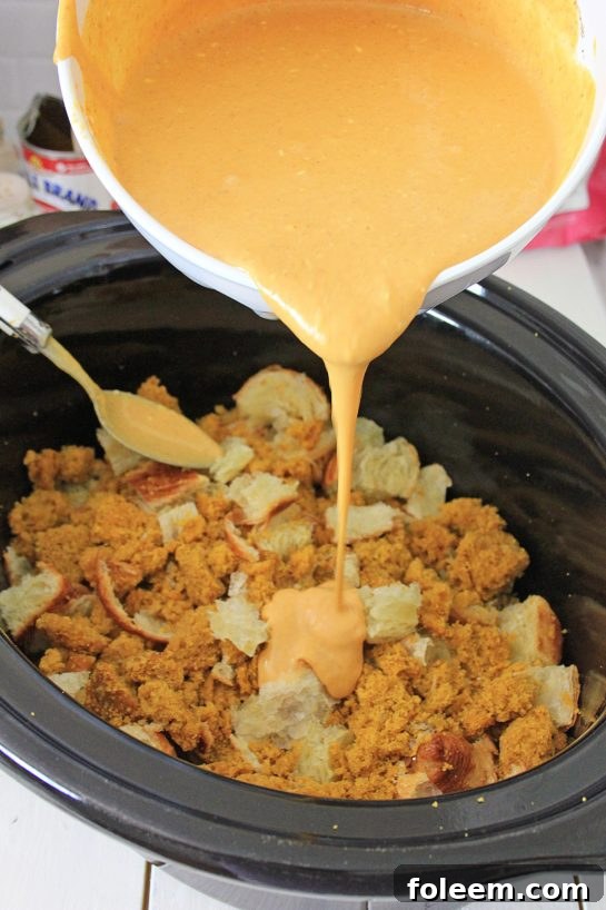 Transferring the pumpkin custard mixture over cubed croissants and pumpkin muffins in the slow cooker.