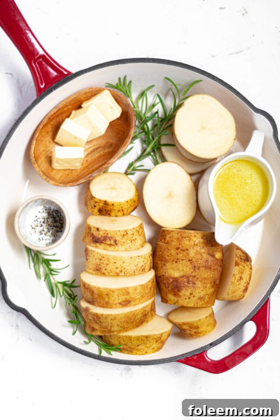 Assortment of fresh ingredients for melting potatoes, including Russet potatoes, rosemary, garlic, and butter