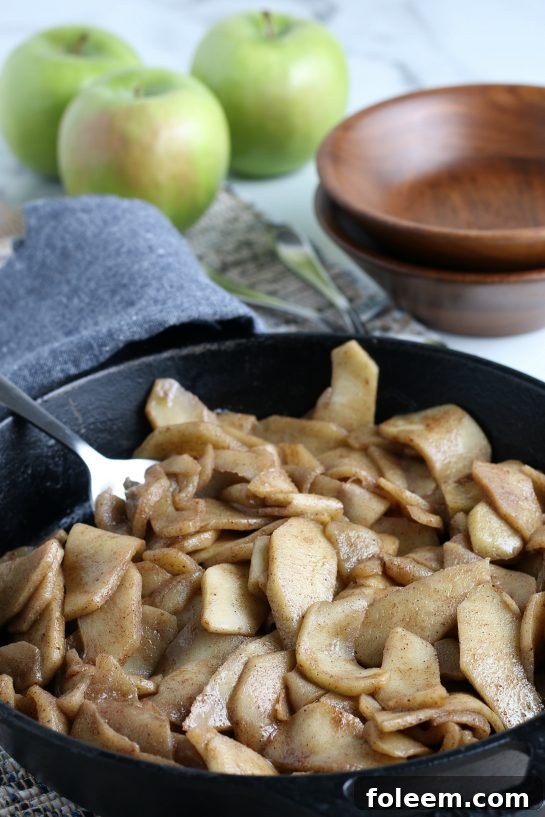 A close-up shot of tender fried apple wedges, perfectly caramelized and coated in a sweet, spiced glaze, served hot.