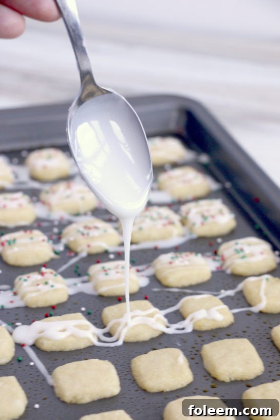 Gently drizzling the freshly made icing over the baked Christmas Sugar Cookie Bites.