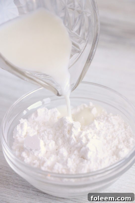 Combining the wet ingredients with the dry ingredients in a mixing bowl for the Christmas Sugar Cookie Bites dough.