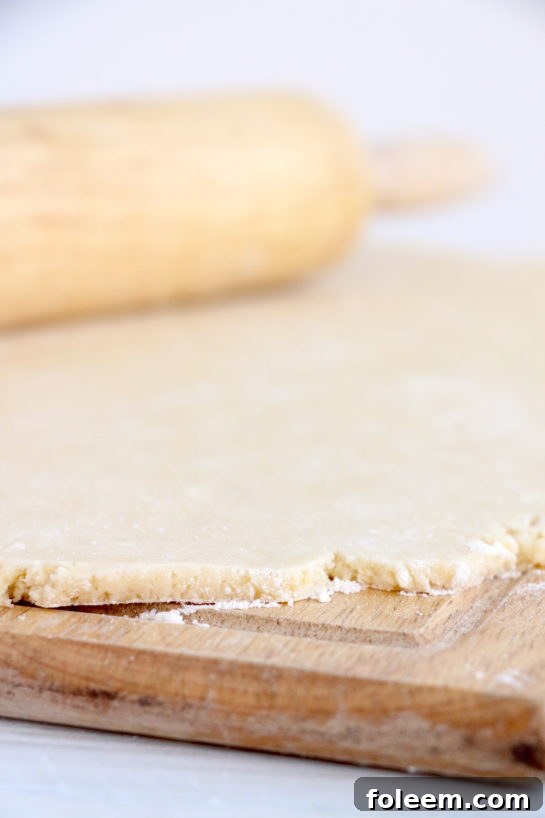 Rolling out the perfectly mixed dough on a floured surface for the easy Christmas Sugar Cookie Bites recipe.
