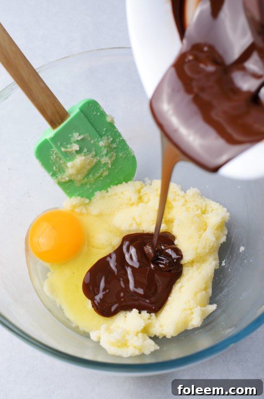 Pouring melted chocolate into wet ingredients for cookies