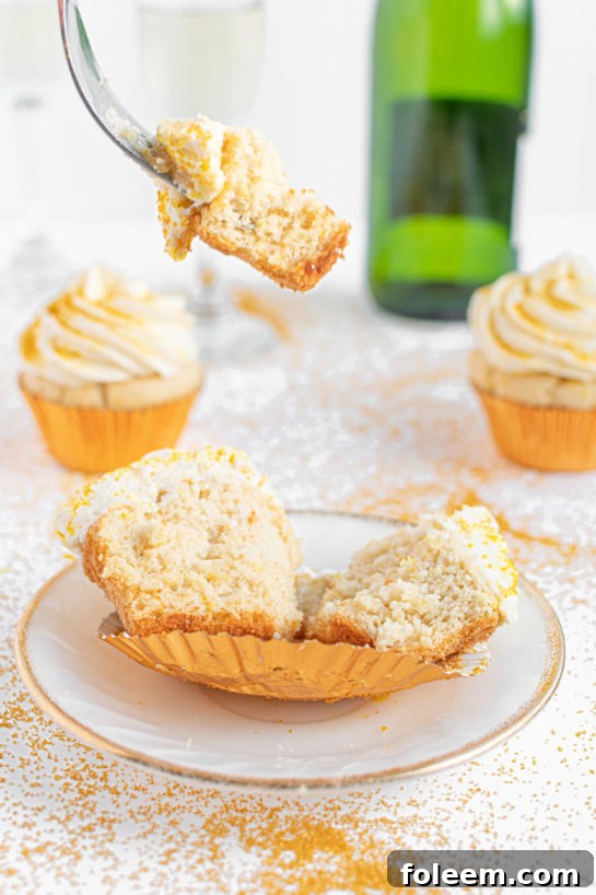 A close-up view of a Champagne Cupcake cut open, showcasing its fluffy texture and moist interior, ready to be enjoyed.
