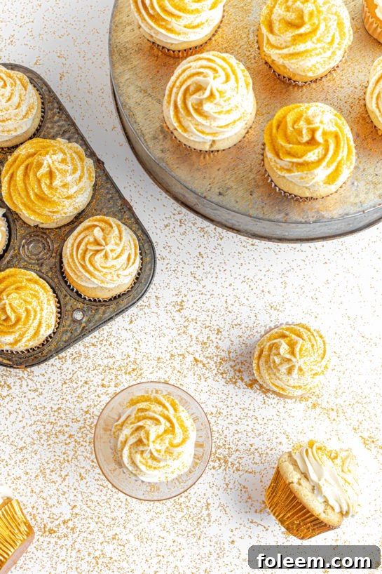Overhead shot of a platter of finished Champagne Cupcakes, glistening with frosting and gold sprinkles, ready for a party.