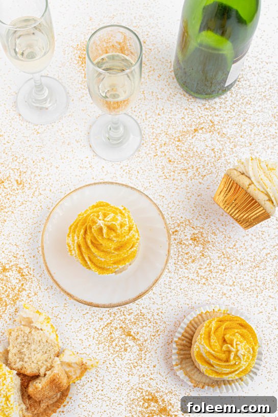 Overhead shot of freshly baked Champagne Cupcakes, elegantly frosted and topped with glittering gold sprinkles.