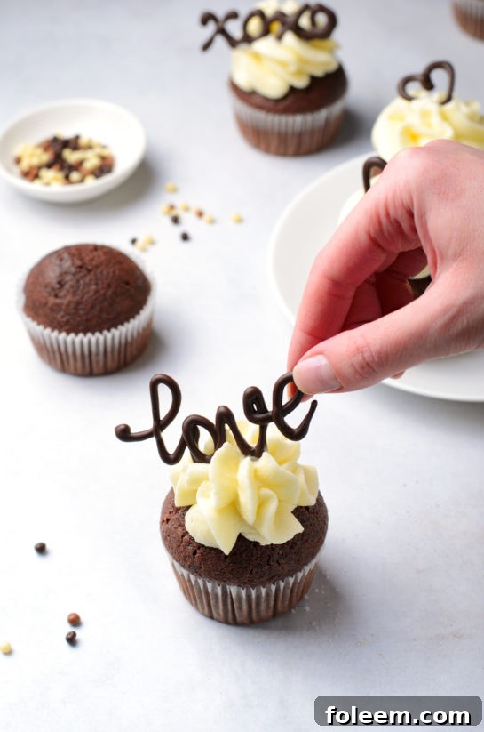 Gently placing delicate chocolate letter toppers on the frosted Valentine's Day cupcakes.