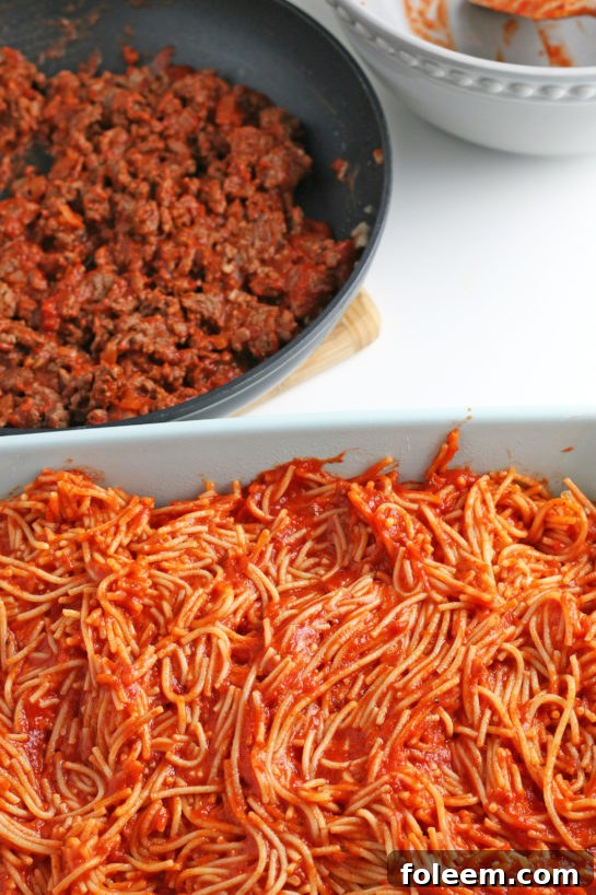 The first foundational layer of our baked spaghetti casserole consists of perfectly coated pasta mixed with a savory red sauce.