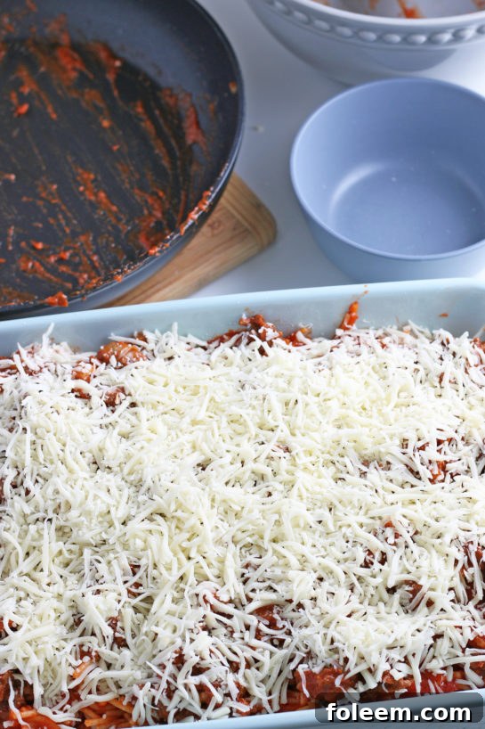 The final layer of shredded mozzarella cheese generously tops the casserole, ready to melt into a golden, bubbly crust in the oven.