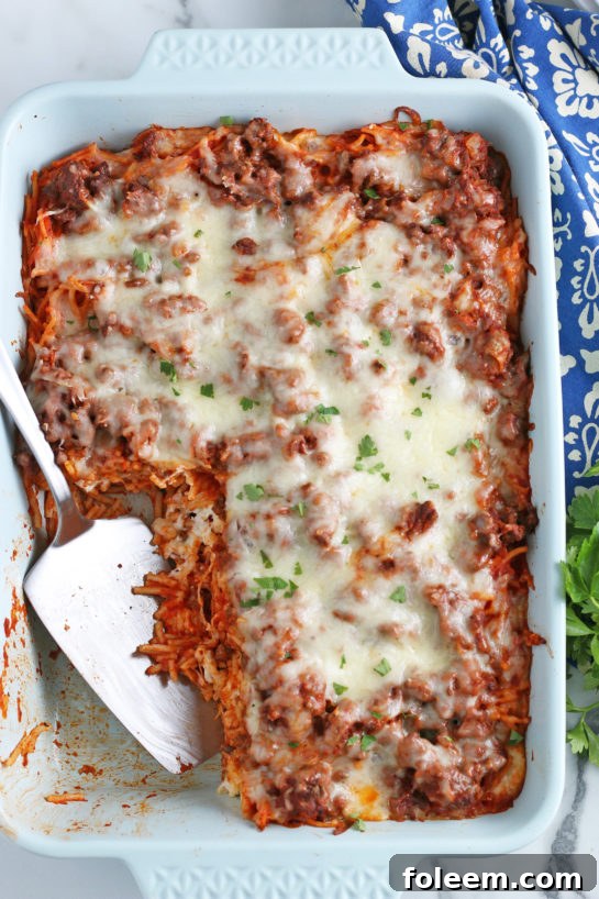 A satisfying overhead shot of the finished baked spaghetti casserole, with several generous servings already portioned out, revealing its delicious layers.