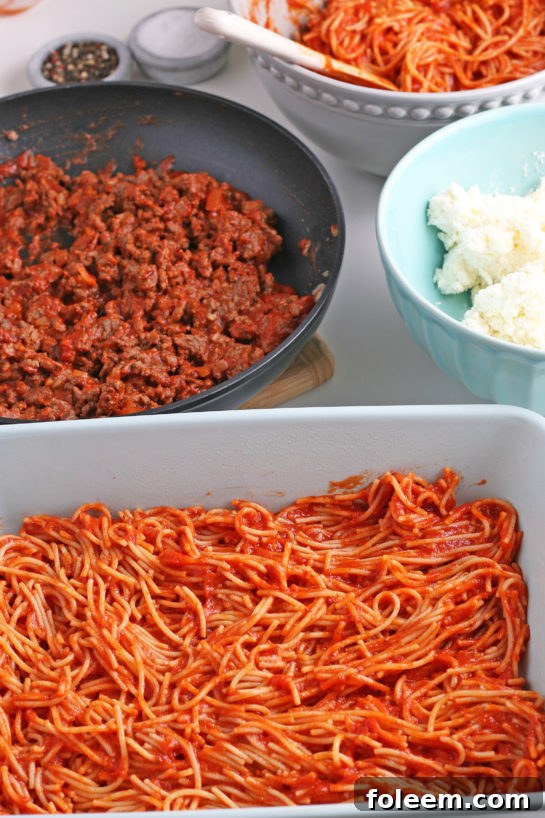 Cooked spaghetti is gently folded into the luscious pasta sauce, ensuring every strand is perfectly coated for the casserole.