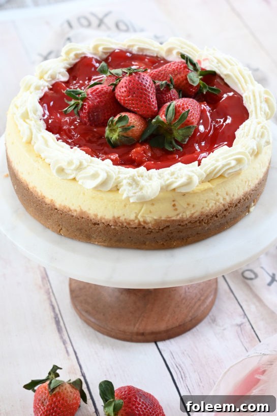 A beautifully sliced Strawberry Topped New York-Style Cheesecake, showcasing its creamy texture and vibrant strawberry sauce