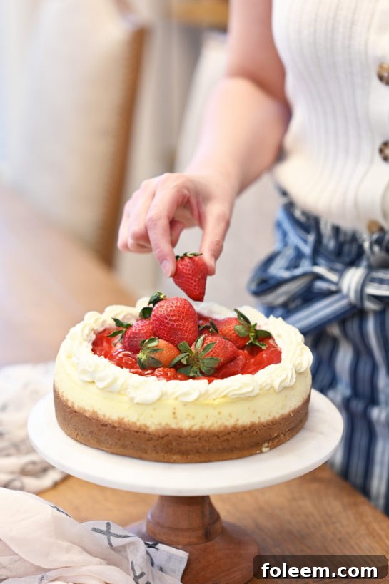 A close-up view of the Strawberry Topped New York-Style Cheesecake, showcasing the glistening strawberry sauce and golden crust