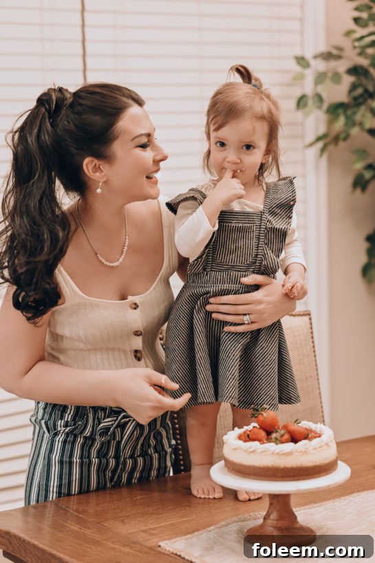A child joyfully tasting a slice of the homemade New York-Style Cheesecake with strawberry topping