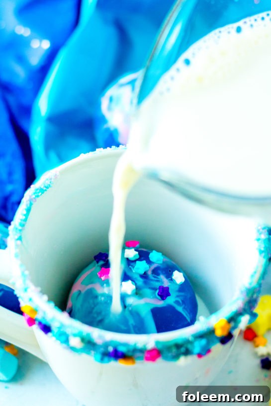 Pouring hot milk over a Galaxy Hot Chocolate Bomb in a mug.