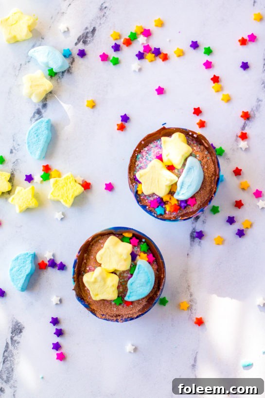 Overhead shot of finished Galaxy Hot Chocolate Bombs with marshmallows and sprinkles.