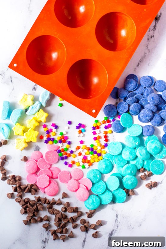 Overhead shot of ingredients laid out for making Galaxy Hot Chocolate Bombs: chocolate, candy melts, hot cocoa mix, marshmallows, sprinkles.