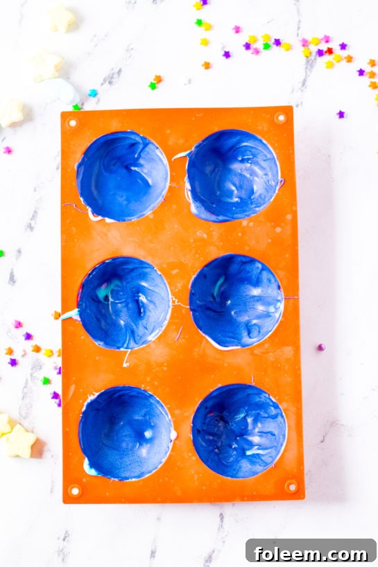 Silicone molds with blue melted chocolate for the Galaxy Hot Chocolate Bombs.