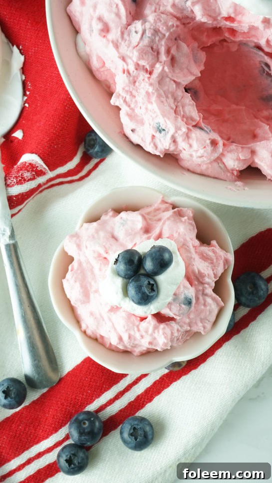 Overhead shot of an individual serving of Patriotic Red White and Blue Fluff Salad in a glass bowl.