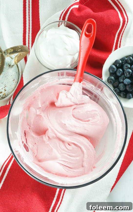 Mixing Jell-O powder and whipped cream in a large bowl for the Red White and Blue Fluff Salad.
