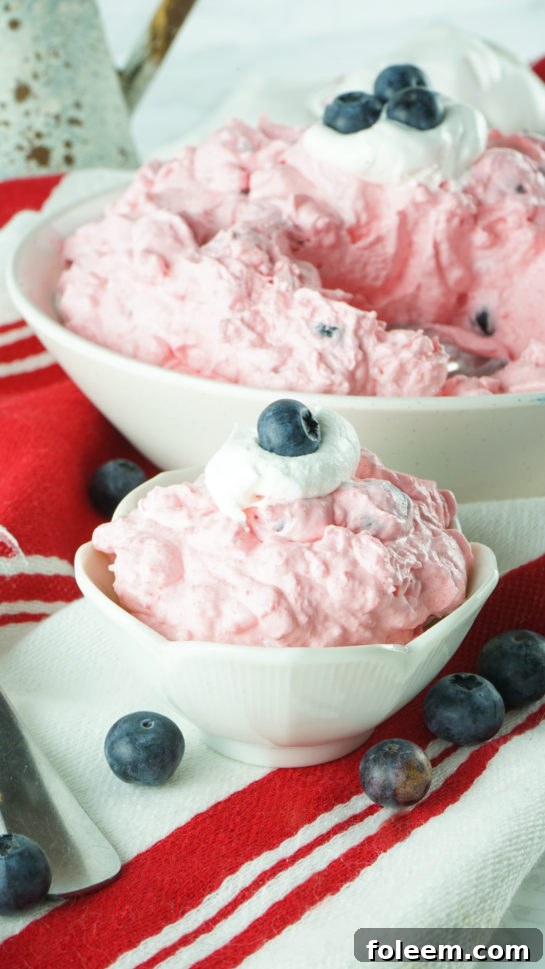 Individual serving of Red White and Blue Fluff Salad in a clear bowl, showcasing layers of fruit and cream.