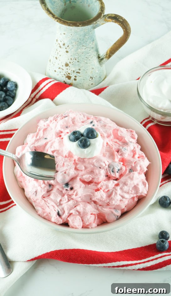 Serving bowl of Easy Red White and Blue Fluff Salad, garnished and ready for a summer party.