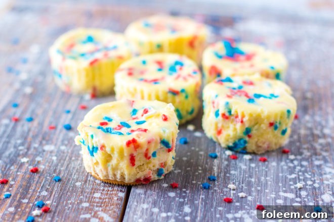 Simple Mini Red, White, and Blue Cheesecakes recipe layered with a Golden Oreo crust and creamy tangy cheesecake. Top with sprinkles & whipped cream for the perfect patriotic dessert for 4th of July!