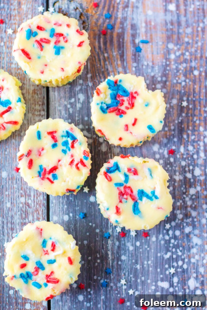 Red, White, and Blue Mini Cheesecakes recipe layered with a Golden Oreo crust and creamy tangy cheesecake. Top with sprinkles and whipped cream for the perfect dessert for 4th of July!