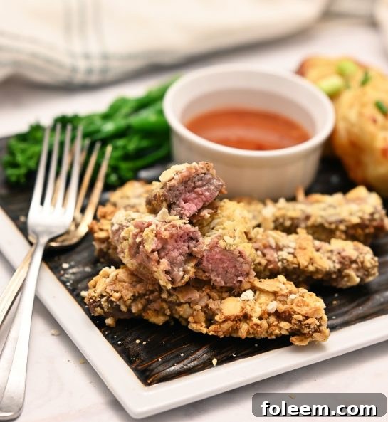 Close-up of golden and crispy deep-fried finger steaks, showcasing their texture and readiness for dipping in sauces.