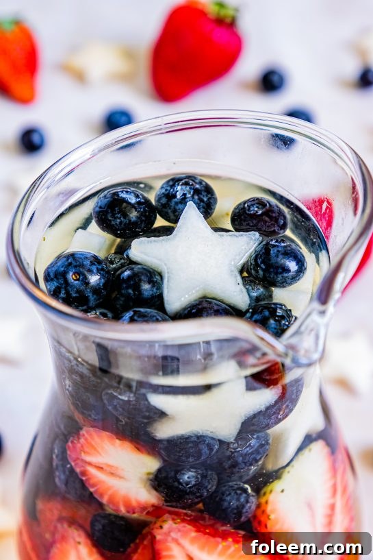 Close-up of my Patriotic Sangria recipe this summer to enjoy a cocktail while beating the heat at the same time! With fresh blueberries, strawberries, white grape juice, brandy, and wine, it's perfect for Flag Day, 4th of July or Memorial Day!
