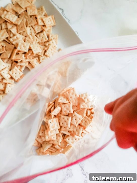 Premium mini saltines being poured into a large zip-top bag, ready for seasoning.
