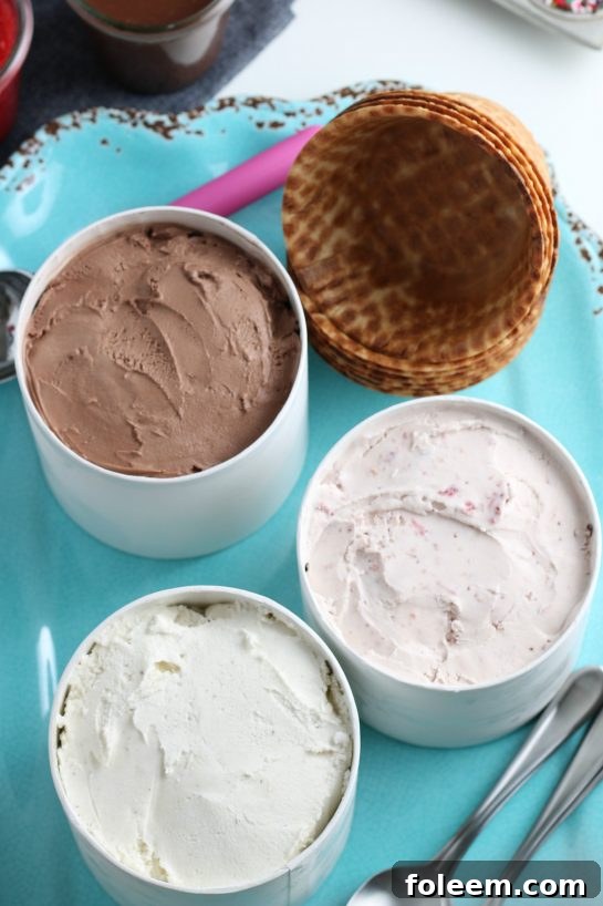 Overhead shot of an organized ice cream sundae bar with diverse toppings in clear jars.