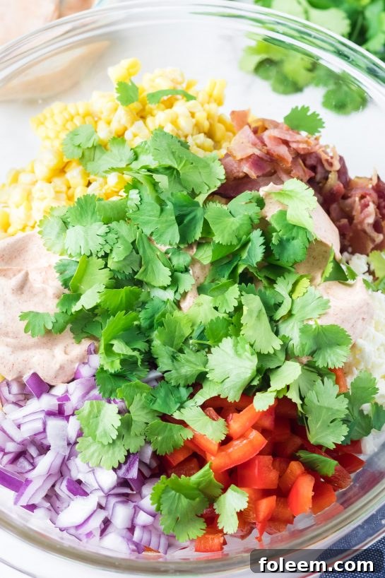 Close-up of vibrant ingredients for Mexican Street Corn Pasta Salad, including corn, bell pepper, and cilantro.