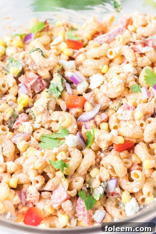 Thoroughly mixing all components of the Mexican Street Corn Pasta Salad to combine flavors.