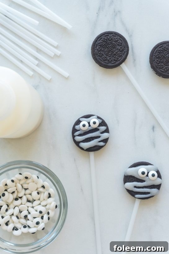 Mummy Oreo Pops with candy eyes placed, drying on a baking sheet.