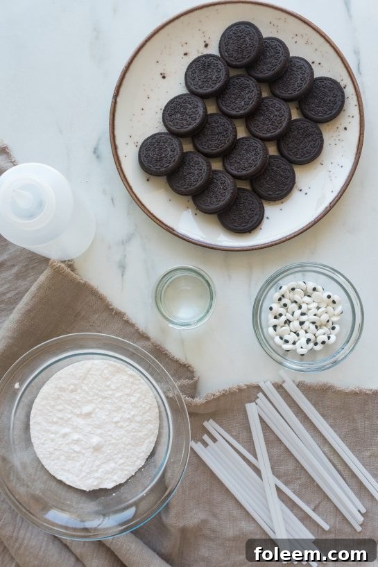 Ingredients for Mummy Oreo Pops, including Oreos, powdered sugar, water, candy eyes, and lollipop sticks.
