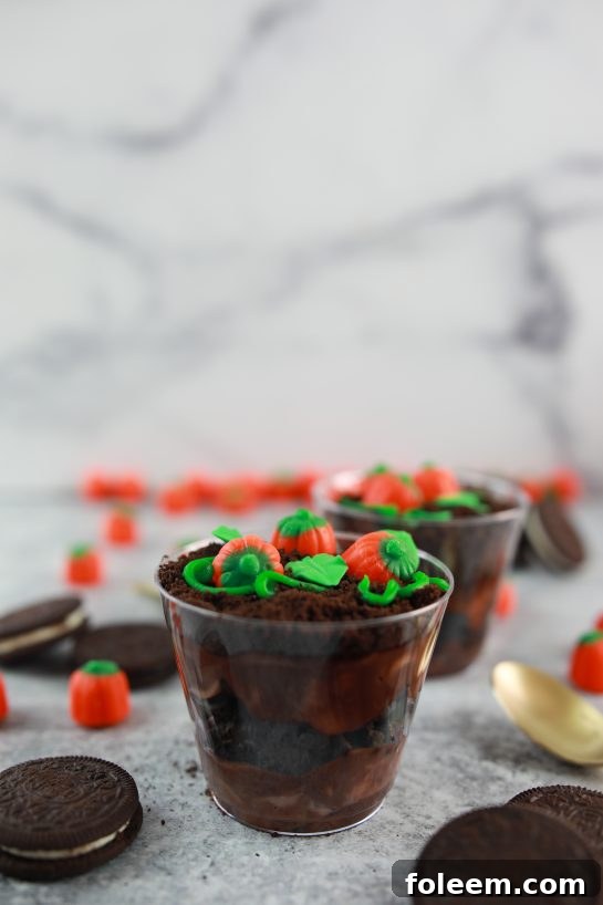 A selection of Pumpkin Patch Dirt Cups displayed on a rustic wooden board, ready for a fall party