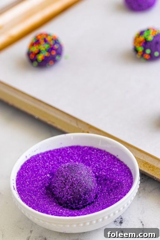 Rolling cookie dough balls in sanding sugar for Halloween Witch Hat Cookies.