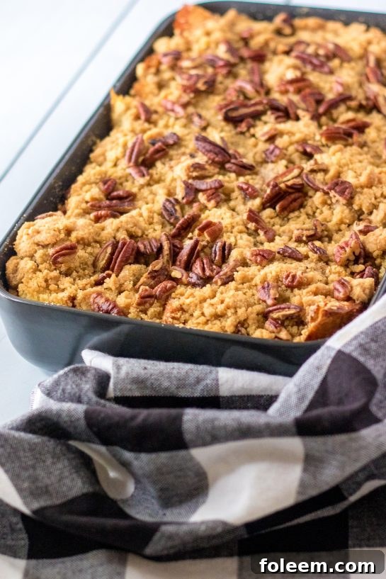 A delicious close-up of a perfectly baked Sweet Potato French Toast Casserole, garnished with powdered sugar and a drizzle of maple syrup, ready to be served for a festive occasion.