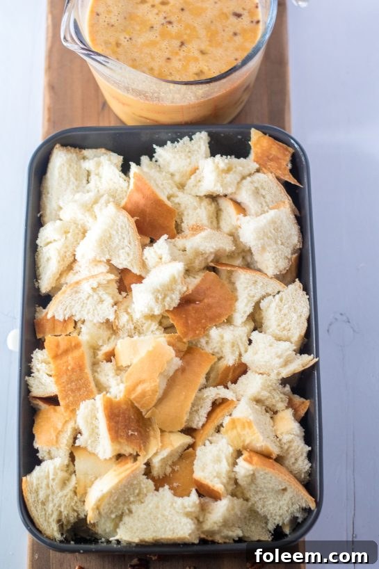 Cubed bread, the foundation of the casserole, carefully torn and spread in a baking dish, ready to absorb the flavorful sweet potato custard.